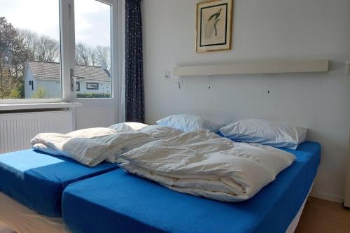 1 cama no hecha en un dormitorio con ventana en Ipharra, en Cadzand