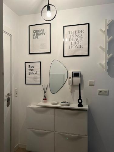 La salle de bains est pourvue d'une coiffeuse avec un miroir et de quelques photos. dans l'établissement Charmant logement - CDG & Astérix, à Vémars