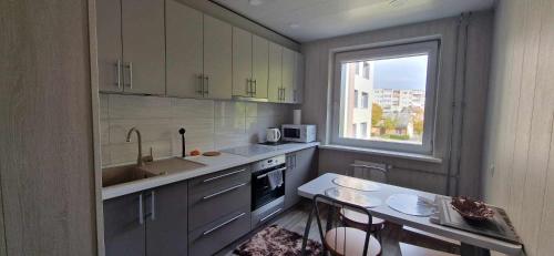 a kitchen with a table and a sink and a window at Dubysa Apartments in Raseiniai