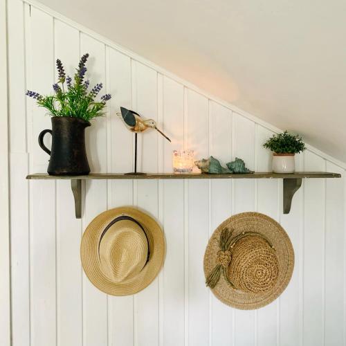two shelves on a white wall with hats and flowers at FF1001 Sommerhus ved Vesterhavet in Billum