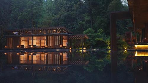 a house in the middle of the water at night at 青城山坐忘森林疗愈酒店 in Dujiangyan