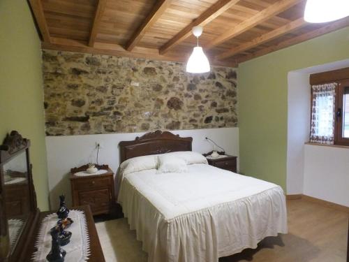a bedroom with a bed and a stone wall at Apartamentos Rurales Casa Llucas in San Julián