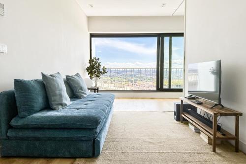 a living room with a blue couch and a flat screen tv at Dragão Rooftop in Porto