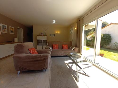 un salon avec un canapé et une table en verre dans l'établissement Saint Palais sur Mer - BELLE MAISON IDÉALEMENT SITUÉE 5 min PLAGE DE NAUZAN, à Saint-Palais-sur-Mer