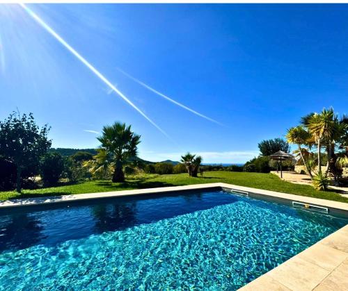 - une piscine avec un ciel bleu et des palmiers dans l'établissement Villa La Cadière avec piscine, à Laouque