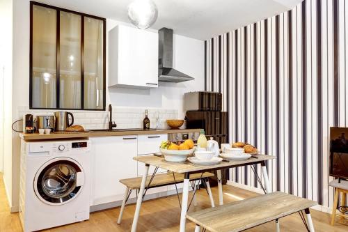 une cuisine avec une table et une machine à laver dans l'établissement Charme contemporain pres de La Villette - 4P, à Paris