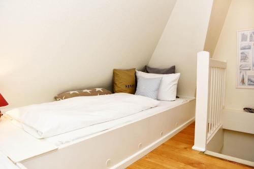 a white bed with pillows on it in a room at Hüs Frieda in Keitum