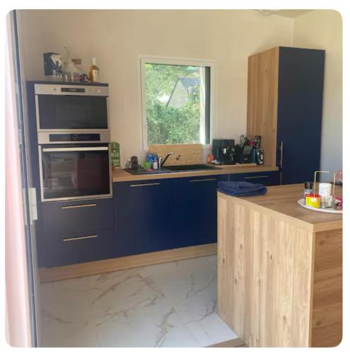 une cuisine avec des placards bleus et une fenêtre dans l'établissement Maison paisible, à Tréméoc