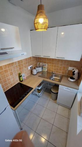 une petite cuisine avec des armoires blanches et un évier dans l'établissement A l'aube des bains, à Lamalou-les-Bains