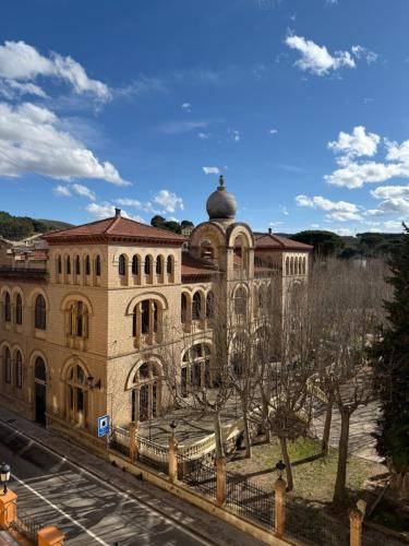 a large brick building with trees in front of it at Hotel Parque Balneario Termas Pallares in Alhama de Aragón