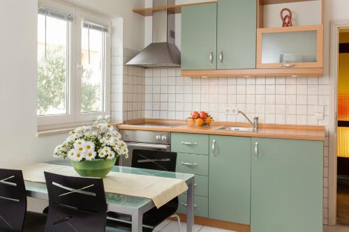a kitchen with blue cabinets and a table with flowers on it at Apartments and rooms Mlikota in Promajna