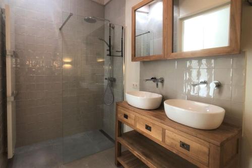 een badkamer met wastafel en douche bij Nia Domo, Ringdijk Noord 22a in Cadzand