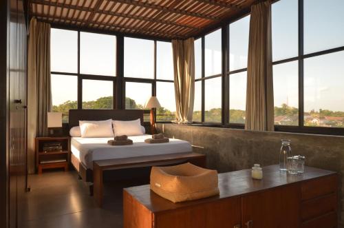 a bedroom with a bed and large windows at Ohmmstay - Rumah Pendopo in Tanjungtirto