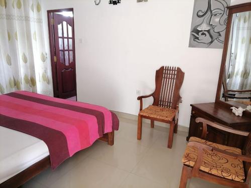 a bedroom with a bed and a chair and a table at JJ Villa & Tours in Aluthgama