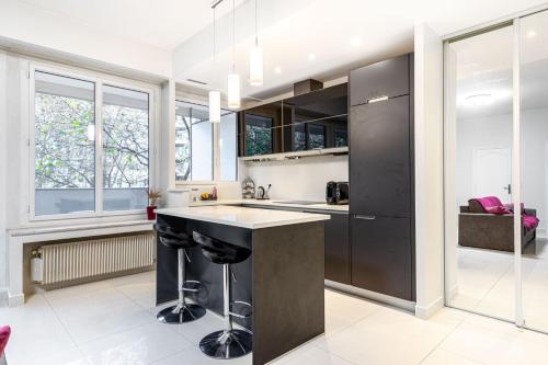 une cuisine avec un îlot noir au milieu dans l'établissement GuestReady - Bright charm with a terrace, à Paris