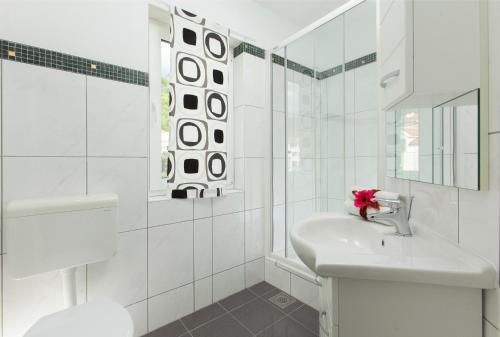 a white bathroom with a sink and a shower at Apartments and rooms Mlikota in Promajna