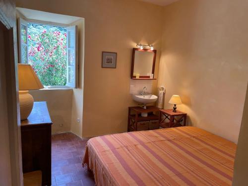 a bedroom with a bed and a sink and a window at Maison ancienne rénovée avec vue sur mer et Cap Corse in Centuri
