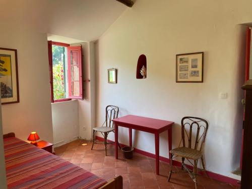 a room with a red table and two chairs at Maison ancienne rénovée avec vue sur mer et Cap Corse in Centuri