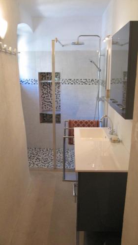 La salle de bains est pourvue d'une douche et d'un lavabo blanc. dans l'établissement Maison ancienne rénovée avec vue sur mer et Cap Corse, à Centuri