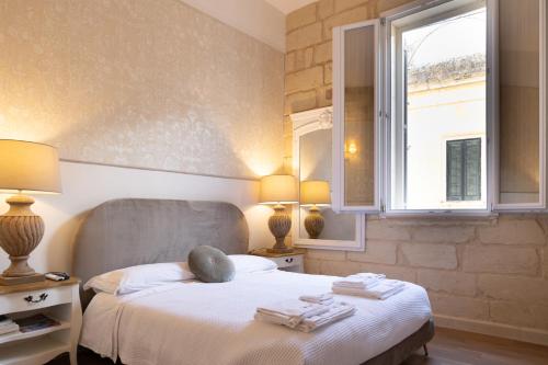 a bedroom with a bed with two lamps and a window at Fjore di Lecce, camere & caffè in Lecce