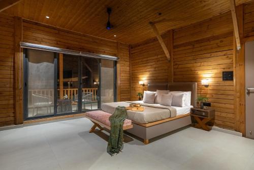 a bedroom with a bed and a large window at Stayscape Smultronstalle 6BHK Igatpuri in Zarvar