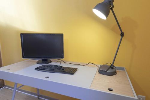 a desk with a computer monitor and a lamp on it at Ide'Alsace in Eguisheim