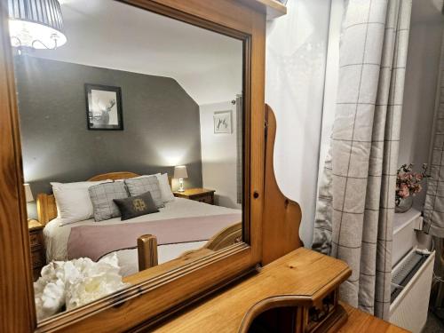a mirror reflection of a bedroom with a bed at Holly Cottage in Hutton le Hole