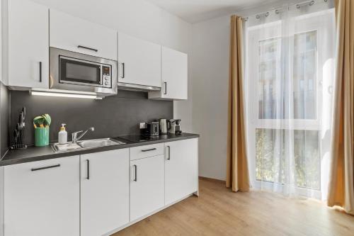a white kitchen with a sink and a microwave at 4 Min to Metro I 12 Min to Inner City I Top Wifi in Vienna