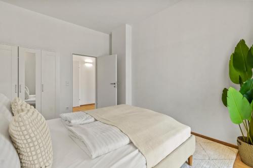a white bedroom with a bed and a plant at 4 Min to Metro I 12 Min to Inner City I Top Wifi in Vienna