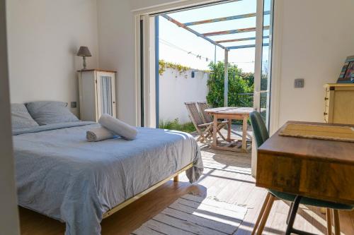 a bedroom with a bed and a table and a balcony at magnifique villa avec piscine - 8 personnes - paracou in La Chaume