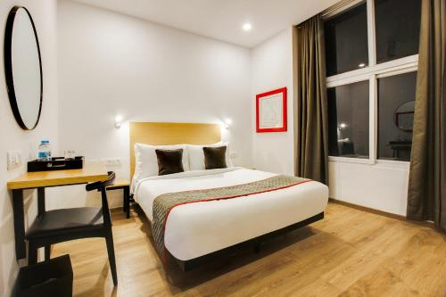 a hotel room with a bed and a desk and window at Super townhouse moosapet Rcc Prime in Hyderabad