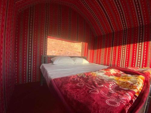 a bedroom with a bed with red walls and a window at Wadi Rum safari camp in Wadi Rum