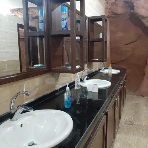a bathroom with two sinks and a black counter at Wadi Rum safari camp in Wadi Rum