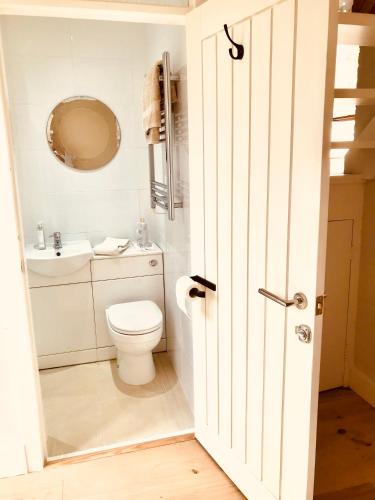a white bathroom with a toilet and a sink at Peaceful Scandi Garden room in Falmouth