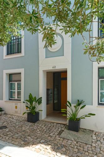 a white building with two plants in front of it at Baía Terraza Cascais Apartment in Cascais