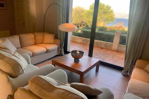 - un salon avec des canapés, une table et une grande fenêtre dans l'établissement Villa des Îles d'Or - 14pers - Swimming pool & sea view, à Hyères