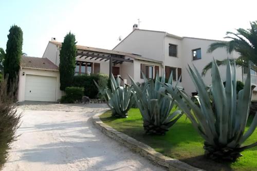 une maison avec des plantes en agave devant elle dans l'établissement Villa des Îles d'Or - 14pers - Swimming pool & sea view, à Hyères