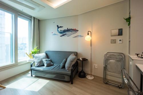 a living room with a blue chair and a dinosaur on the wall at Gwangan antique summer accommodations the ocean in Busan