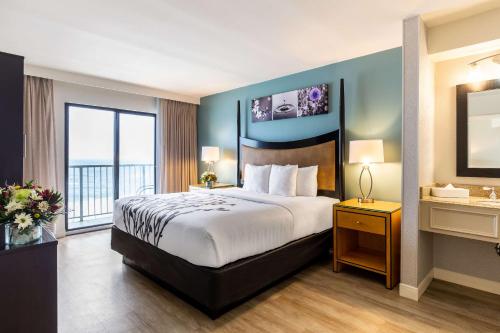 a hotel room with a bed and a large window at Sleep Inn on the Beach in Orange Beach