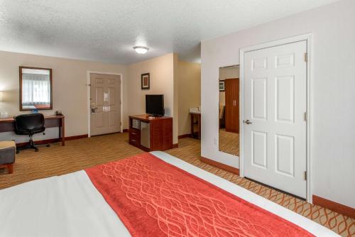 a bedroom with a bed and a desk and a door at Comfort Inn Mount Shasta Area in Weed