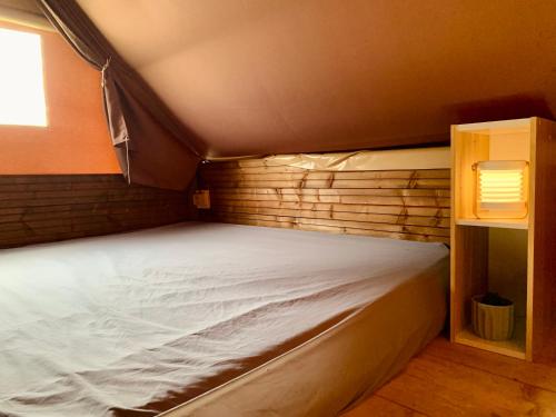 a bed in a small room with a wooden wall at Camping Point Vert in Serrières-de-Briord