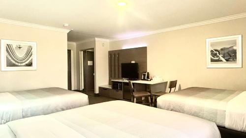 a hotel room with two beds and a desk at Quality Inn & Suites Los Angeles Airport - LAX in Inglewood