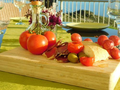 a wooden cutting board with tomatoes and cheese on a table at Villa Lilly in Podgora