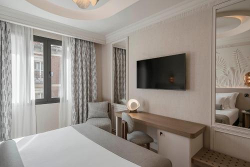 a hotel room with a bed and a desk and a television at Vincci Centrum in Madrid