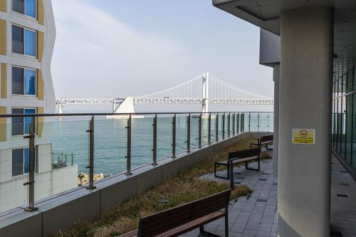 a balcony with benches and a view of a bridge at Gwangan antique summer accommodations the ocean in Busan