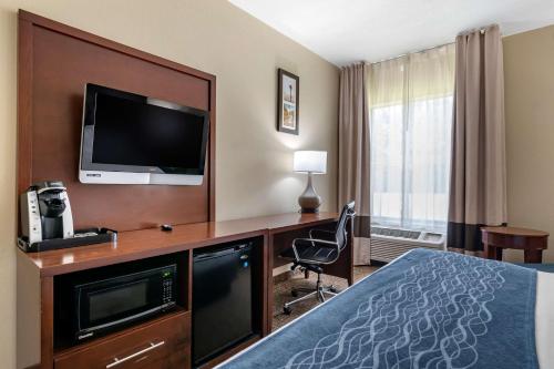 a hotel room with a bed and a desk with a television at Comfort Inn & Suites Junction City - near Fort Riley in Junction City