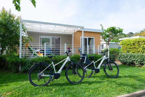 two bikes parked in the grass in front of a house at Camping Village Baia Azzurra in Castiglione della Pescaia