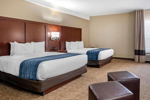 a hotel room with two beds and a chair at Comfort Inn & Suites Junction City - near Fort Riley in Junction City