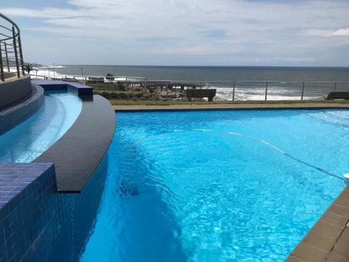 a large blue swimming pool with the ocean in the background at Whale Rock Beauty in Margate
