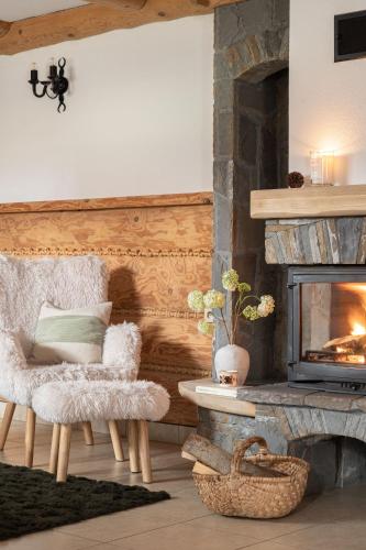 a living room with a fireplace and a chair at Willa Podhalanka Jacuzzi & sauna - drewniany dom dla 20 osób in Biały Dunajec